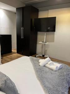 ein Schlafzimmer mit einem Bett mit Handtüchern und einem TV in der Unterkunft Modern Stratford Apartment with Parking in London