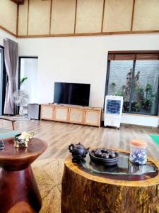 una sala de estar con una gran habitación con mesa y TV en Sakura Mura Retreat and Wellness, en Phu Quoc