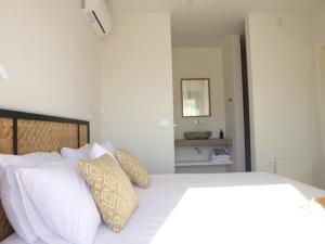 a bedroom with a white bed with pillows and a mirror at Villa Hermes in Pogoniá