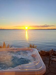 a hot tub in front of the water with the sunset at Relaxing cottage with spectacular view, Sauna and Spa Pool in Kircubbin