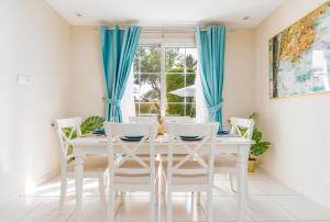 a white dining room with blue curtains and a white table and chairs at Lux BnB Springs Villa Private Garden in Dubai