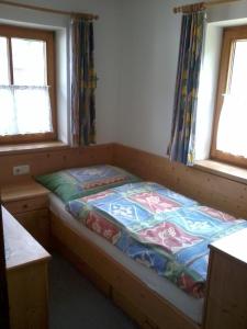 a bed in a room with two windows at Lechnerhäusl in Maria Alm am Steinernen Meer