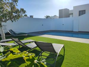 - un groupe de chaises assises à côté de la piscine dans l'établissement Villa Carpe Diem en Puerto del Carmen, à Puerto del Carmen