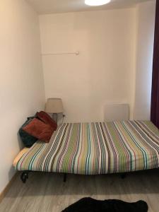 ein kleines Schlafzimmer mit einem Bett mit gestreifter Decke in der Unterkunft Charmant appartement 2 chambres dans le centre historique in Orange