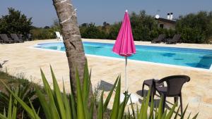 - un parasol rose à côté de la piscine dans l'établissement Eremo del Dottó, à Alberobello