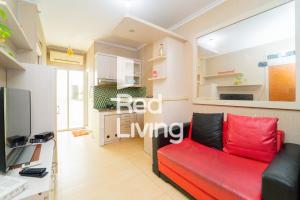ein Wohnzimmer mit einem roten Sofa und einer Küche in der Unterkunft RedLiving Apartemen Cibubur Village - Lily's Room Tower C in Depok