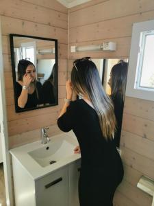 a woman standing in front of a bathroom mirror at Camping Hameau Des Cannisses in Gruissan