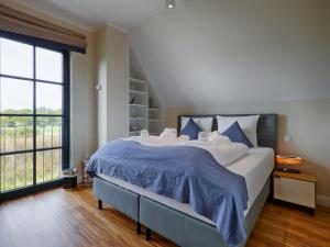 1 dormitorio grande con 1 cama grande con sábanas azules en Reetland am Meer - Premium Reetdachvilla mit 3 Schlafzimmern, Sauna, Kamin und Massagesessel F05, en Dranske