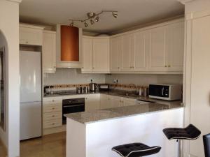 Una cocina con gabinetes blancos y encimera. en Jumilla III, en Orihuela Costa