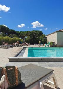 una piscina con un banco frente a ella en Camping Hameau Des Cannisses, en Gruissan