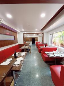 restauracja z czerwonymi kanapami i stołami w pokoju w obiekcie Rapid Lakme Executive Hotel w mieście Pune