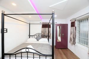 Deekay Villa Yelagiri By Lexstays في ييلاجيري: غرفة نوم مع سرير بأربعة أعمدة واضاءة أرجوانية
