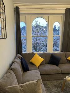 a couch in a living room with three windows at Complete Osborne House by Prescott Apartments in Bristol