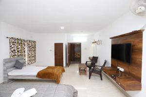 Deekay Villa Yelagiri By Lexstays في ييلاجيري: غرفة نوم بسرير وتلفزيون وأريكة