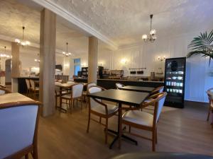 a dining room with tables and chairs and a kitchen at Hotel du Louvre in Cherbourg en Cotentin