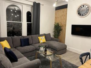 a living room with a couch and a clock on a wall at Complete Osborne House by Prescott Apartments in Bristol