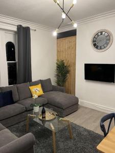 sala de estar con sofá, mesa y reloj en Complete Osborne House by Prescott Apartments en Bristol