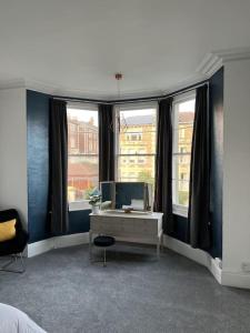 Complete Osborne House by Prescott Apartments في بريستول: غرفة نوم مع مكتب مع جهاز كمبيوتر ونوافذ