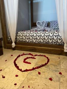 een bed met een hart gemaakt van rode bloemen op de vloer bij L'EXCELLENCE AVIGNON - Suite LUXE SAUNA, HAMMAM & JACCUZZI in Avignon