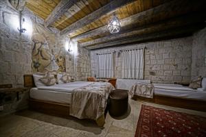 a bedroom with two beds in a stone building at Risus Cave Suites in Goreme