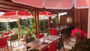 un restaurante con mesas, sillas rojas y sombrillas en Le sapin rouge, chambres d'hôtes - restaurant - bar, en Artigues