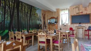 ein Restaurant mit Holztischen und -stühlen und einer Tafel in der Unterkunft Le sapin rouge, chambres d'hôtes - restaurant - bar in Artigues