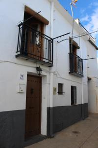 biały budynek z drzwiami i balkonem w obiekcie Casa Estrella de las nieves La Alpujarra w mieście Bérchules