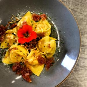 a plate of ravioli with a red flower on it at Hotel Landgasthof Lärchenwald in Collepietra