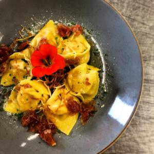 un plato de ravioles con una flor roja. en Hotel Landgasthof Lärchenwald, en Collepietra