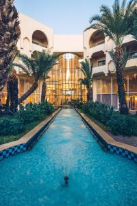 a swimming pool in front of a building with palm trees at Iberostar Averroes in Hammamet