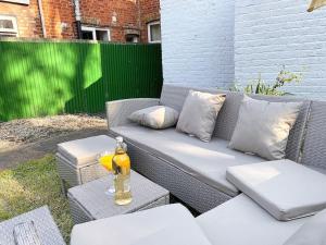 a grey wicker couch with pillows and a bottle of alcohol at Beautiful City Centre Home With Garden and Parking in Oxford