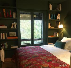een slaapkamer met een bed, een raam en boekenplanken bij le Pullman in Deauville