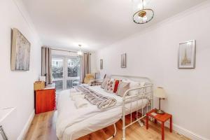 a white bed in a room with a window at Beautiful 4-bedroom house in Victoria Park in London