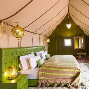 a bedroom with a green bed in a tent at Mourad desert camp in Merzouga