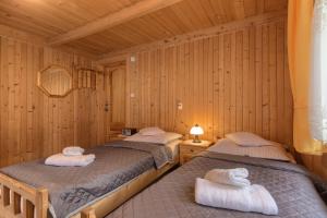 two beds in a room with wooden walls at Gościniec u Marzeny in Bukowina Tatrzańska