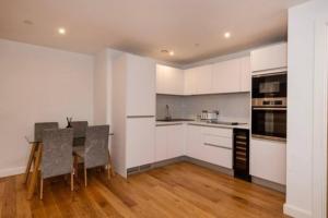 a kitchen with white cabinets and a table and chairs at 1 Bed In Birmingham City Centre in Birmingham