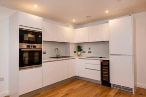 a white kitchen with white appliances and wooden floors at 1 Bed In Birmingham City Centre in Birmingham