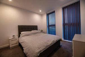 a bedroom with a bed and two large windows at 1 Bed In Birmingham City Centre in Birmingham