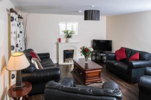 a living room with black leather furniture and a fireplace at Island Winds Along The Atlantic Way in Killala