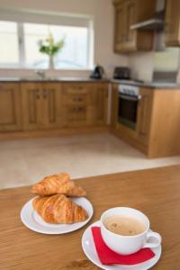 uma chávena de café e croissants numa mesa na cozinha em Island Winds Along The Atlantic Way em Killala