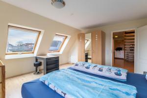 Schlafzimmer mit einem blauen Bett, einem Schreibtisch und einem Fenster in der Unterkunft Haus Liberty 2 in Büsum