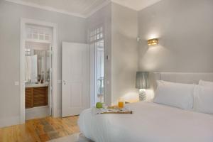 a white bedroom with a large bed and a bathroom at Casa do Presidente in Lisbon