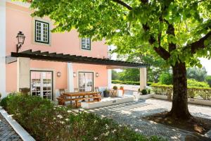 a patio in front of a pink house with a tree at Casa do Presidente in Lisbon