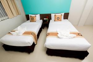 duas camas num quarto de hotel com almofadas brancas e castanhas em Royal Asia Hotel Pratunam em Bangkok