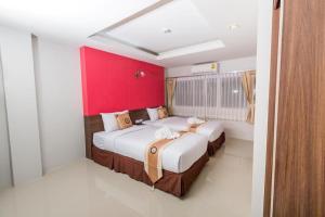 um quarto com 2 camas e uma parede vermelha em Royal Asia Hotel Pratunam em Bangkok