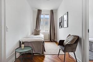 Sanders Square - Spacious Six-Bedroom Apartment Near Amalienborg في كوبنهاغن: غرفة نوم بسرير وكرسي ونافذة