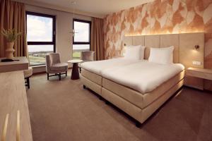 a hotel room with a large bed and a desk at Van der Valk Hotel Gorinchem in Gorinchem