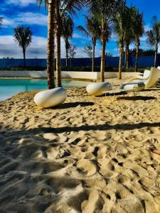 una spiaggia con sedie, palme e acqua di Blissful escape at Azure North Pampanga a San Fernando