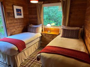 two beds in a room with a window at Pucks Glen Lodges in Dunoon