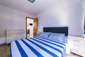 1 dormitorio con 1 cama con edredón de rayas azul y blanco en Maspalomas,Flipper, en Maspalomas 7 fotos más